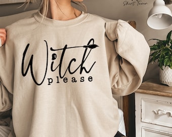 May include: A beige sweatshirt with the text "Witch Please" in black lettering. The text is in a cursive font with a small broom and ghost graphic above the word "Witch".