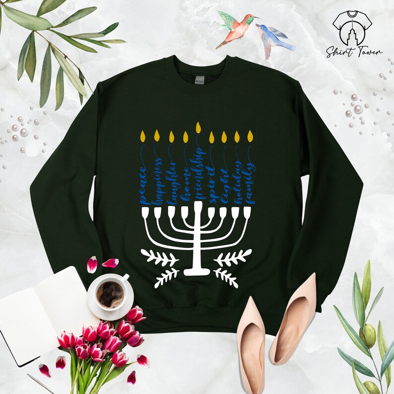Puede incluir: Una sudadera de color verde oscuro con un dise&ntilde;o de menor&aacute; blanco y texto azul que dice "paz, felicidad, risa, amor, amistad, esp&iacute;ritu, especial, luz, vacaciones, familia".