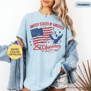 Op de afbeelding: Lichtblauw T-shirt met een distressed grafische afbeelding ter viering van de 250e verjaardag van de Verenigde Staten. Het ontwerp toont de Amerikaanse vlag, het Vrijheidsbeeld en een adelaar. Tekst luidt "United States of America" en "250th Anniversary 1776-2026".