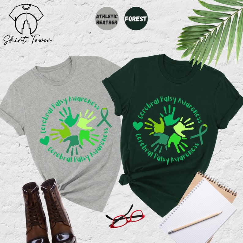 May include: Two t-shirts with a green and white design of handprints in a circle with the text "Cerebral Palsy Awareness". One shirt is green and the other is gray.