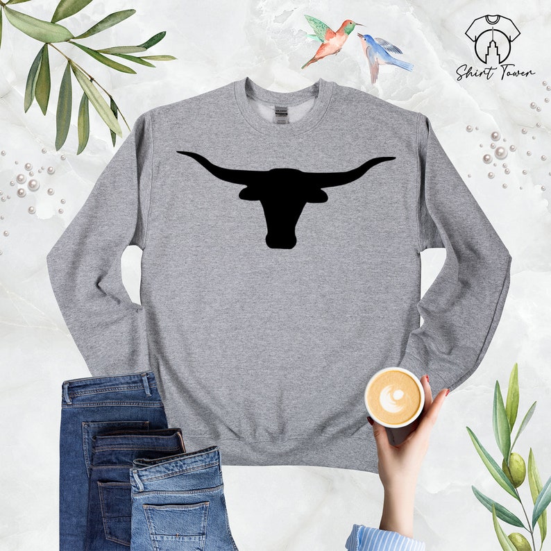 May include: A gray sweatshirt with a black silhouette of a longhorn bull's head with horns. The sweatshirt is on a white background.