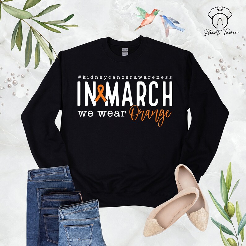 Puede incluir: Sudadera negra con el texto "#kidneycancerawareness IN MARCH we wear Orange" y una cinta naranja.