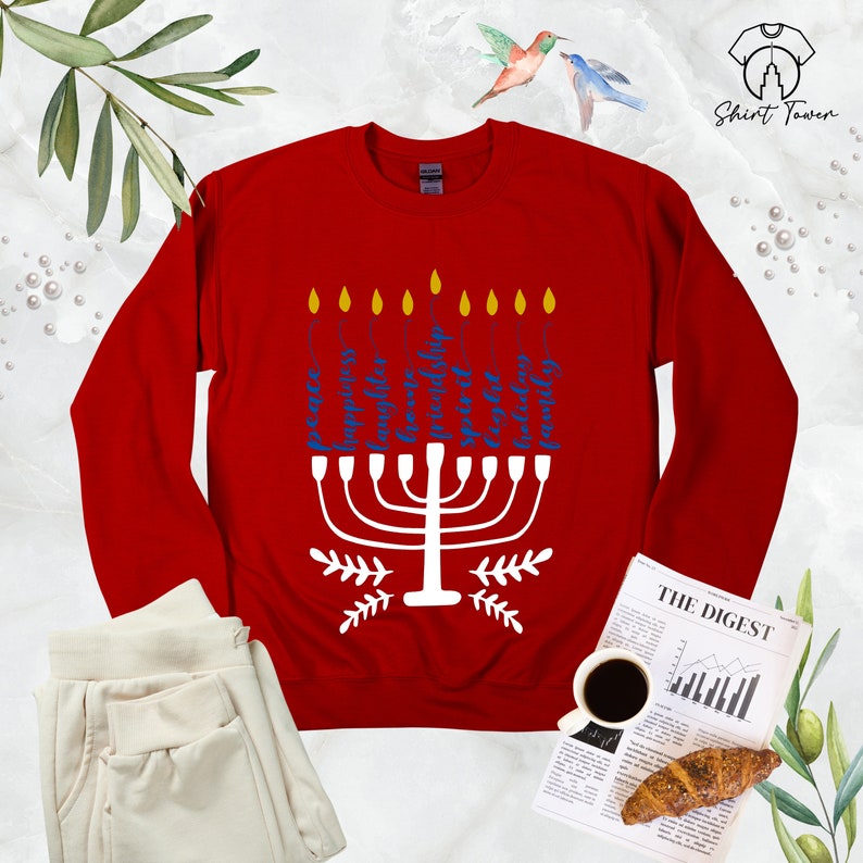 Puede incluir: Sudadera roja con un dise&ntilde;o de menor&aacute; blanco y texto azul que dice "Paz, Compasi&oacute;n, Alegr&iacute;a, Familia, Libertad, Bondad, Esperanza, Fortaleza y Comunidad".