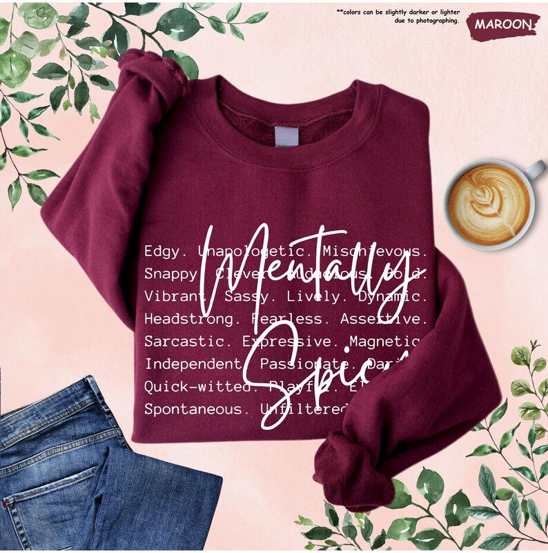 May include: Maroon sweatshirt with the words "Mentally Spicy" in white script. The sweatshirt has a crew neck and long sleeves. A cup of coffee and a pair of blue jeans are also in the image.