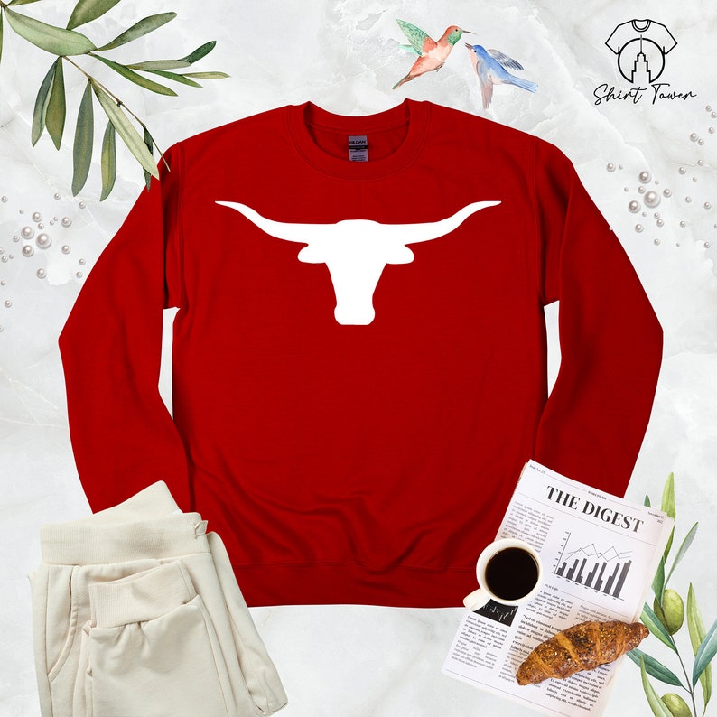May include: Red long-sleeved sweatshirt with a white silhouette of a longhorn bull's head with horns.