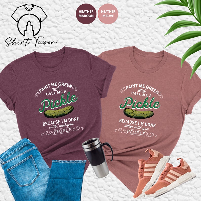 May include: Two t-shirts with a pickle graphic and the text "Paint me green and call me a pickle because I'm done dillin' with you people". The shirts are available in heather maroon and heather mauve.