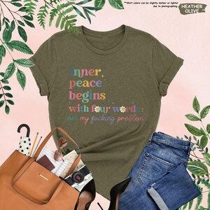 May include: A green heather t-shirt with the text "Inner peace begins with four words: not my fucking problem." in colourful letters.