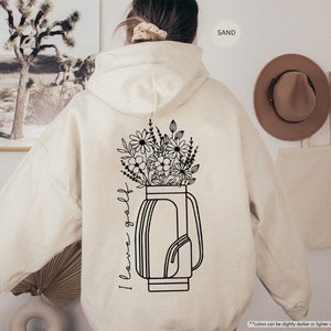 a woman wearing a white hoodie with flowers in a vase on it