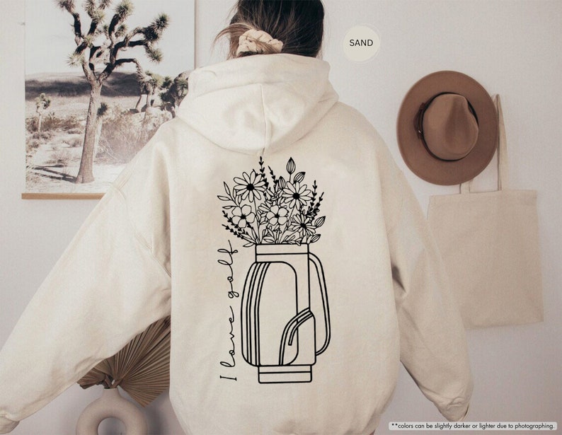a woman wearing a white hoodie with flowers in a vase on it