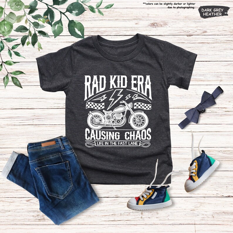 May include: A dark grey heather t-shirt with a white graphic of a motorcycle and the text "Rad Kid Era Causing Chaos Life in the Fast Lane".