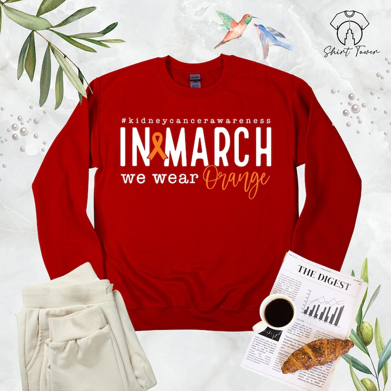 Puede incluir: Sudadera roja de manga larga con el texto "#kidneycancerawareness IN MARCH we wear Orange" y una cinta naranja.