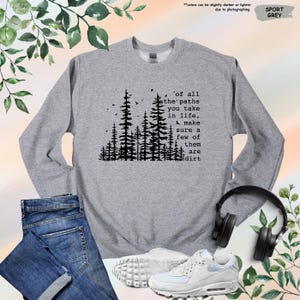 K&ouml;nnte beinhalten: Ein graues Sweatshirt mit einer schwarzen Silhouette eines Waldes und dem Text 'of all the paths you take in life, make sure a few of them are dirt'.