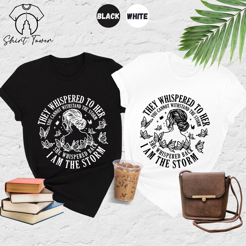 May include: Two t-shirts with a black and white design featuring a woman with butterflies and the text "They whispered to her you cannot withstand the storm she whispered back I am the storm".