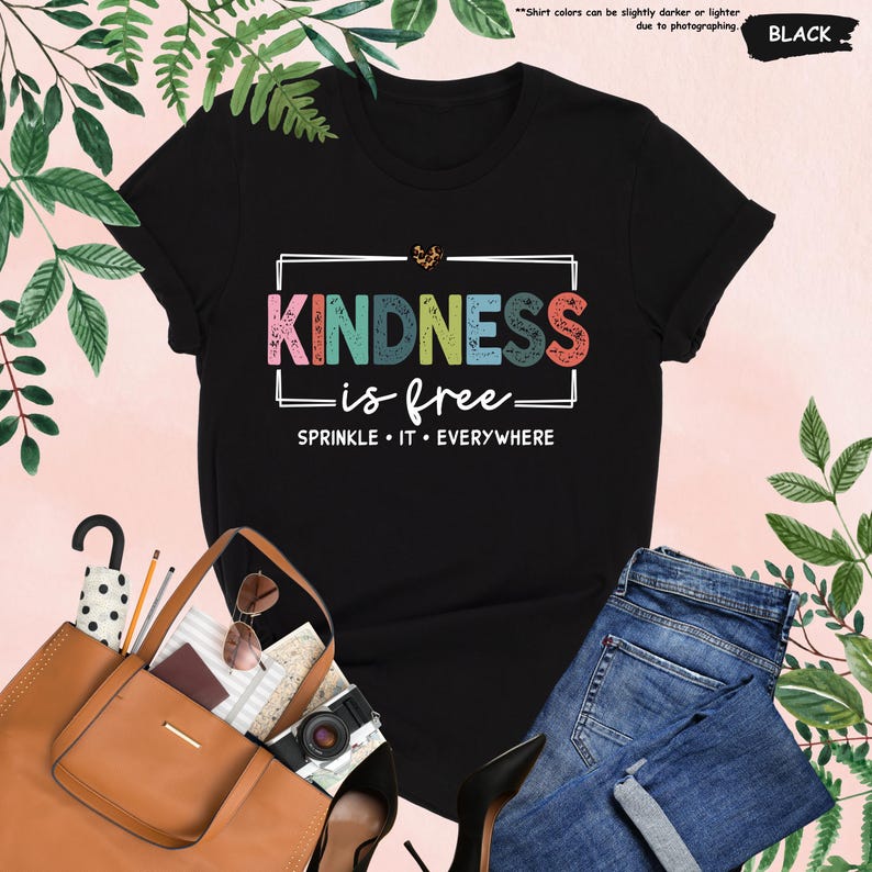 May include: Black t-shirt with the text "KINDNESS is free" in rainbow colors and the text "SPRINKLE IT EVERYWHERE" in white.
