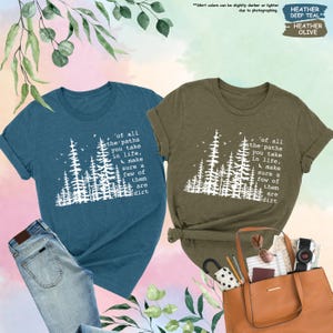K&ouml;nnte beinhalten: Zwei T-Shirts mit einer Waldszene und dem Text 'of all the paths you take in life, make sure a few of them are dirt'. Das Shirt links ist blaugr&uuml;n und das Shirt rechts ist olivgr&uuml;n.