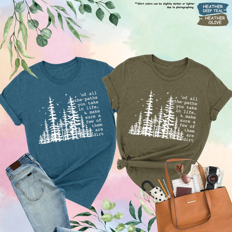 K&ouml;nnte beinhalten: Zwei T-Shirts mit einer Waldszene und dem Text 'of all the paths you take in life, make sure a few of them are dirt'. Das Shirt links ist blaugr&uuml;n und das Shirt rechts ist olivgr&uuml;n.