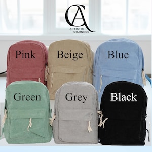 May include: Six corduroy backpacks in different colors: pink, beige, blue, green, grey, and black. Each backpack has a single pocket and a drawstring closure. The backpacks are arranged in two rows of three.