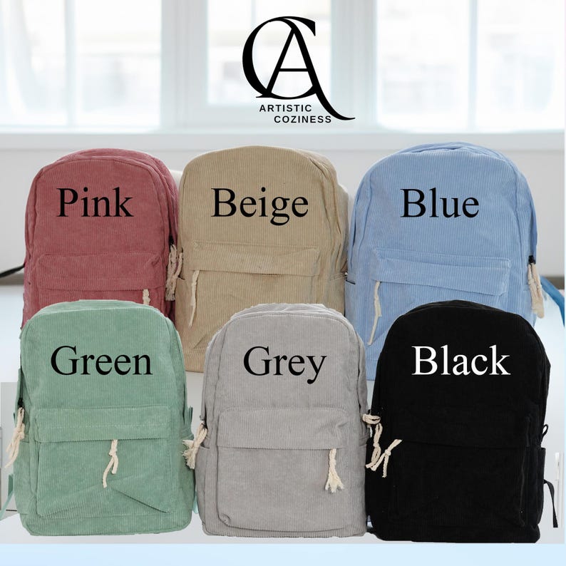 May include: Six corduroy backpacks in different colors: pink, beige, blue, green, grey, and black. Each backpack has a single pocket and a drawstring closure. The backpacks are arranged in two rows of three.