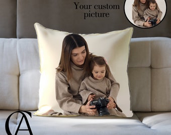 Può includere: Un cuscino bianco con una foto di una madre e una figlia che tengono una macchina fotografica. La madre e la figlia indossano maglioni marroni. Il cuscino ha un bordo giallo chiaro.