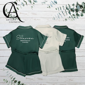 Puede incluir: Tres conjuntos de pijama de satén, dos verdes y uno crema, con mangas cortas y pantalones cortos. Los conjuntos tienen texto personalizado en la parte posterior, incluyendo "Sharron Bridesmaid 10.09.2024", "Bride" y "Maid of Honour".