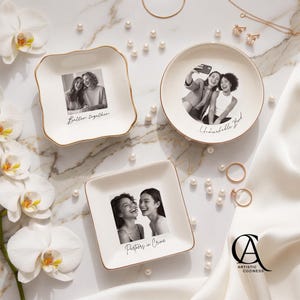 May include: Three white ceramic trinket dishes with gold-toned rims, each featuring a black and white photograph of two people. The dishes are inscribed with the phrases Better together, Unbreakable Bond, and Partners in Crime.