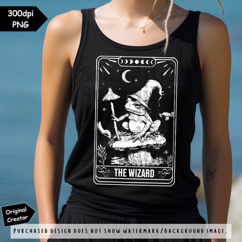 May include: A black tank top featuring a white graphic of a frog wearing a wizard's hat and holding a staff. The graphic is in the style of a tarot card and reads "THE WIZARD" at the bottom.