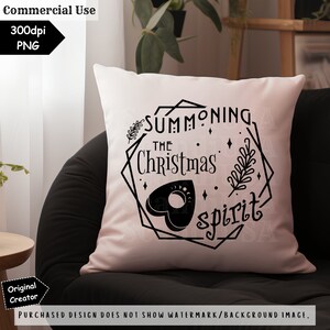 May include: A white pillow with a black design that says "Summoning the Christmas Spirit" with a black heart-shaped Ouija board in the center.