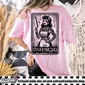 以下が含まれることがあります： ピンクのTシャツに、ナイフを持った女性の白黒のイラストが描かれています。イラストはカードのような枠の中にあり、下部に「THE UNHINGED」という文字があります。