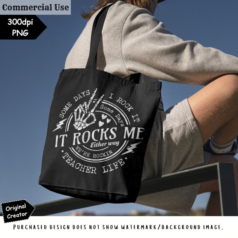 K&ouml;nnte beinhalten: Schwarze Tragetasche mit wei&szlig;em Text und Grafiken. Das Design enth&auml;lt die Worte "IT ROCKS ME" mit einer Skeletthand, die eine Rock-and-Roll-Geste macht. Der Text "TEACHER LIFE" ist ebenfalls enthalten. Die Tasche hat schwarze Tr&auml;ger.