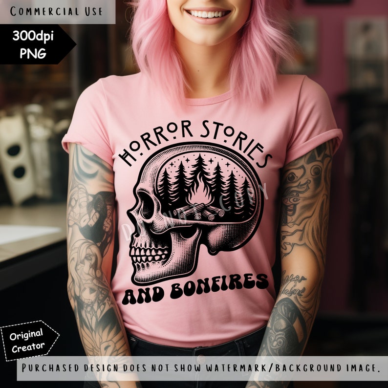 Op de afbeelding: Een roze T-shirt met een zwarte schedelprint. De hersenen van de schedel zijn vervangen door een kampvuursc&egrave;ne met bomen en sterren. De tekst "HORROR STORIES AND BONFIRES" is onder de schedel gedrukt.