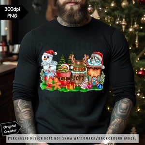 May include: A black long-sleeved shirt with a Christmas-themed design featuring a snowman, gingerbread man, and various holiday-themed cups. The cups are decorated with red and green stripes, snowflakes, and the word "Jolly".
