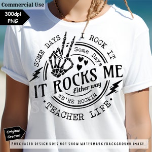 K&ouml;nnte beinhalten: Wei&szlig;es T-Shirt mit schwarzem Aufdruck. Der Aufdruck zeigt eine Skeletthand mit Friedenszeichen, Herzen und den Texten "IT ROCKS ME" und "TEACHER LIFE". Das T-Shirt hat einen l&auml;ssigen Stil.