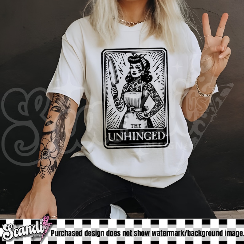 以下が含まれることがあります： ナイフを持った女性の白黒のイラストが描かれた白いTシャツ。イラストはタロットカードのスタイルで、下部に「The Unhinged」と書いてあります。