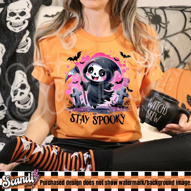 May include: Orange t-shirt featuring a cartoon Grim Reaper with a scythe, tombstones, and bats. The text "Stay Spooky" is below the graphic. The shirt is a Halloween-themed design.