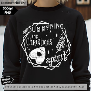May include: A black sweatshirt with a white graphic design that says "Summoning the Christmas spirit". The design features a stylized Ouija board and a sprig of holly.
