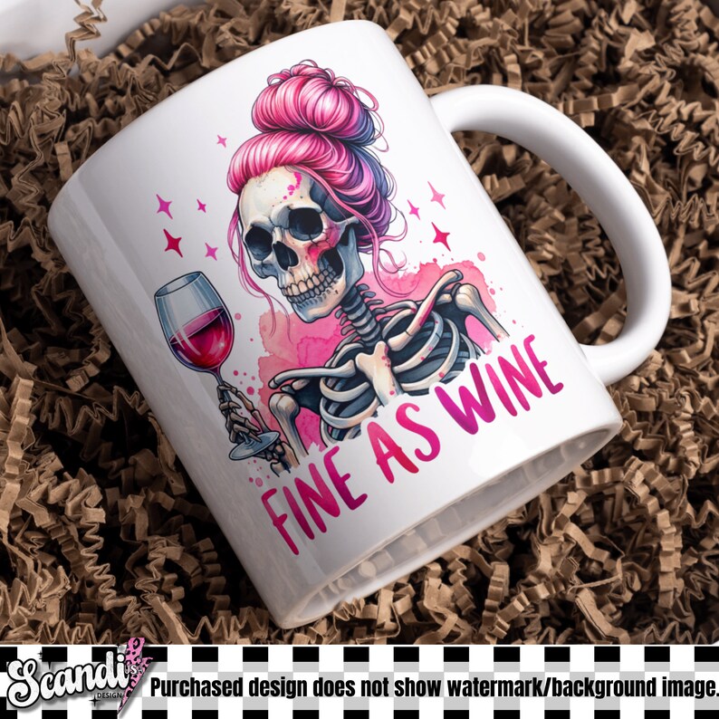K&ouml;nnte beinhalten: Eine wei&szlig;e Keramiktasse mit einem rosa Skelett, das ein Glas Rotwein h&auml;lt. Das Skelett hat rosa Haare in einem Dutt und der Text "Fine as Wine" ist auf die Tasse gedruckt.