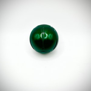 Puede incluir: Una esfera verde oscuro brillante con ranuras verticales. El objeto esf&eacute;rico est&aacute; centrado sobre un fondo blanco, mostrando su superficie reflectante y su forma redondeada. El objeto parece estar hecho de un material s&oacute;lido.