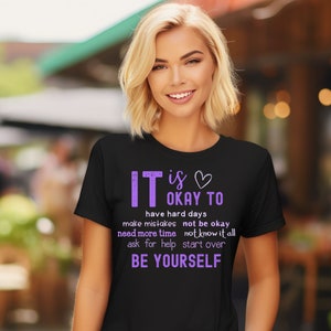 May include: Black t-shirt with purple text that reads "It is okay to have hard days, make mistakes, not be okay, need more time, not know it all, ask for help, start over, Be Yourself."