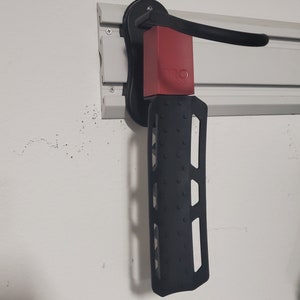May include: A black and red bike rack mounted on a white wall. The rack has a textured black arm and a red base with the word "PRO" printed on it.