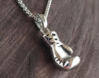 May include: A silver chain necklace with a silver boxing glove pendant. The pendant is detailed with stitching and has a textured surface.