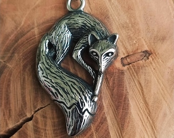 Op de afbeelding: Een zilveren vos-hangerketting met een gedetailleerd ontwerp. De vos is opgerold met zijn staart om zijn lichaam gewikkeld. De ketting is aan een zilveren ketting.