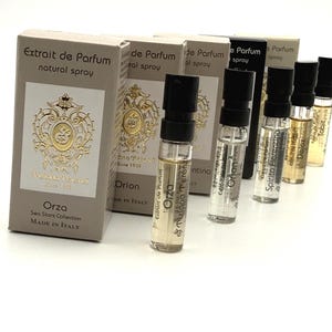 Pode incluir: Uma coleção de amostras de perfume Tiziana Terenzi com as suas caixas retangulares. As caixas são bege com brasões dourados e texto preto, enquanto os pequenos frascos de vidro têm tampas pretas e etiquetas com os nomes Orza, Orion, Spirito Fiorentino, Delox e Tabit.