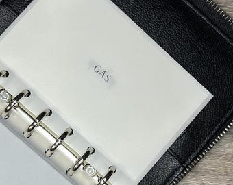 May include: Black zippered binder with a silver ring binder mechanism. The binder is open, revealing a white insert labeled "GAS". The binder is made of textured black material.