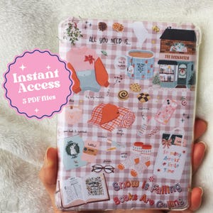 May include: A pink and white checkered background with illustrations of winter-themed objects, including a mug of hot cocoa, a book, a cozy blanket, and a pair of socks. The text "Snow is Falling, Books Are Calling" is printed in a colorful font at the bottom of the image.