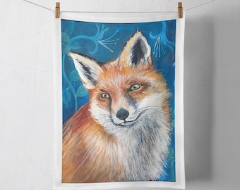 Puede incluir: Una toalla rectangular blanca con una pintura detallada de un zorro. El zorro tiene pelaje naranja y blanco, ojos verdes y una nariz negra. El fondo es azul oscuro con detalles florales. La toalla está colgada de un tendedero.