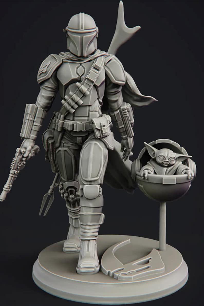 May include: A gray, detailed, 3D printed figurine of a Mandalorian warrior from Star Wars, holding a blaster rifle and carrying a small, gray, 3D printed figurine of a character from the same franchise in a floating pod.