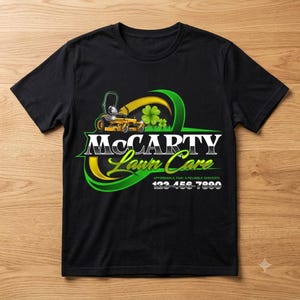 Black crew neck t-shirt with screen printed lawn mowing logo featuring yellow riding mower graphic, green four leaf clover and sweeping gold ribbon — landscaping uniform branding for yard care and mowing businesses