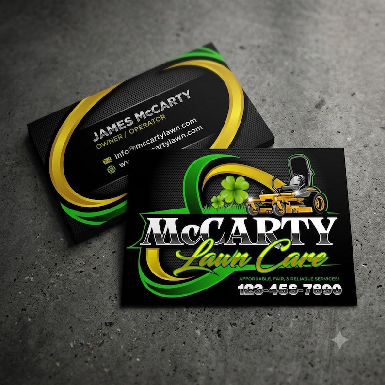 Double sided black business card set on dark concrete surface showing lawn mower logo with green shamrock and gold ribbon on front, owner contact details on back — professional branding for lawn service and yard care businesses