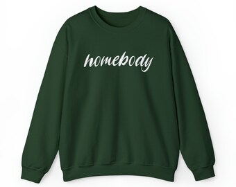 May include: A dark green sweatshirt with the word "homebody" in white cursive script across the chest. The long-sleeved crew neck top is made of a soft material and is suitable for casual wear.