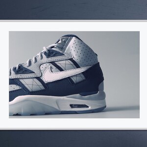 Puede incluir: Primer plano de una zapatilla de caña alta blanca y azul con un logotipo Swoosh blanco. La zapatilla tiene una parte superior texturizada y una suela blanca.